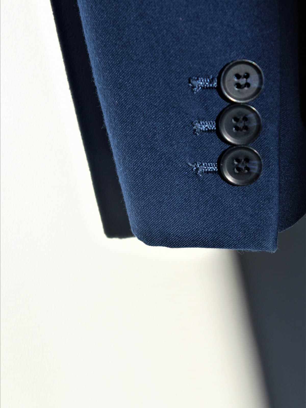 A two-piece suit on a tailor’s form, lit from a single source.
